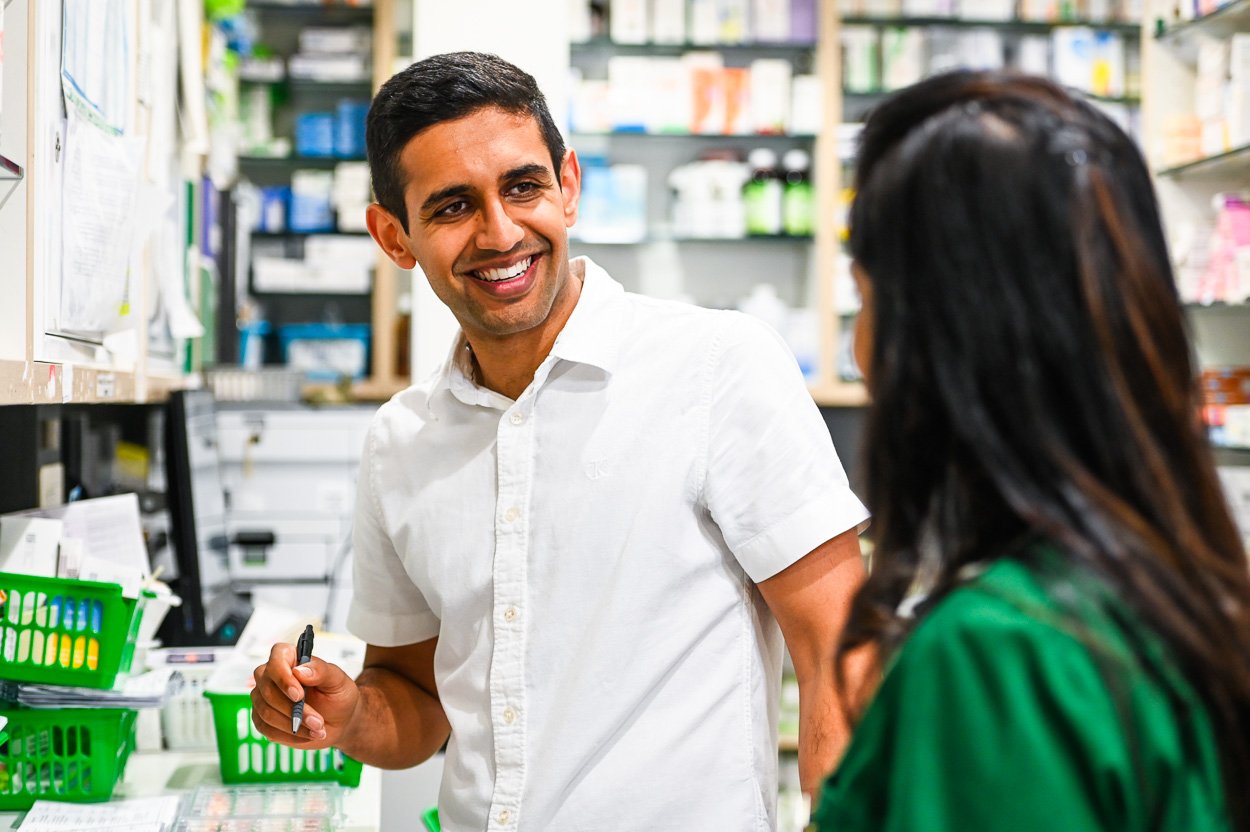 Male pharmacist talking to colleague in a retail pharmacy