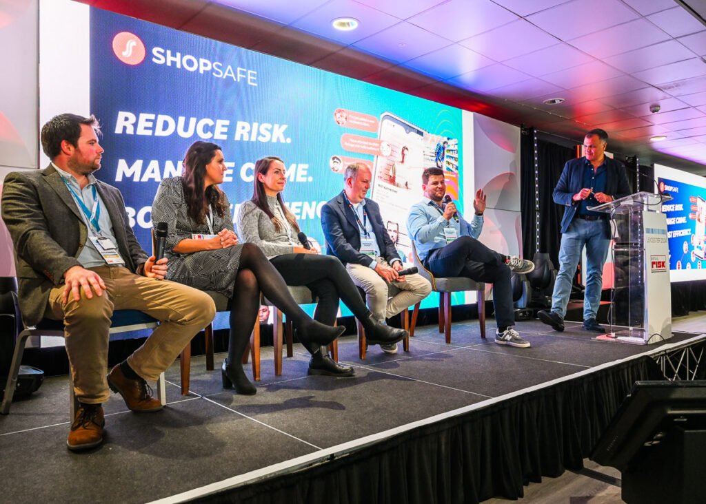 Photograph of speaker panel on stage at a conference