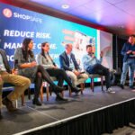 Photograph of speaker panel on stage at a conference