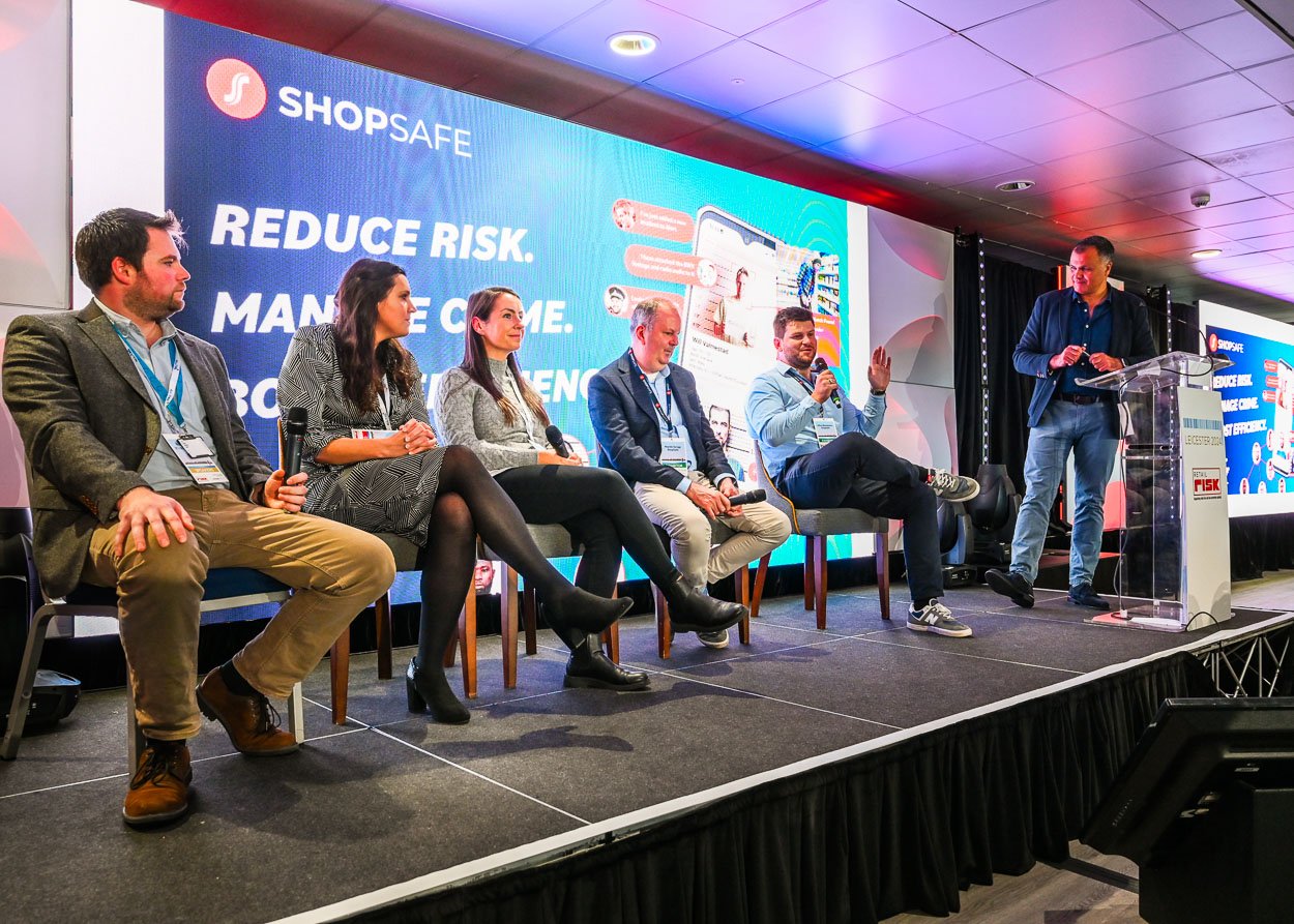 Photograph of speaker panel on stage at a conference