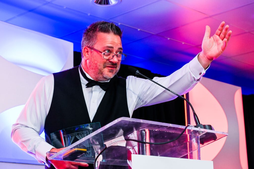 Photograph of excited on-stage presenter at evening event