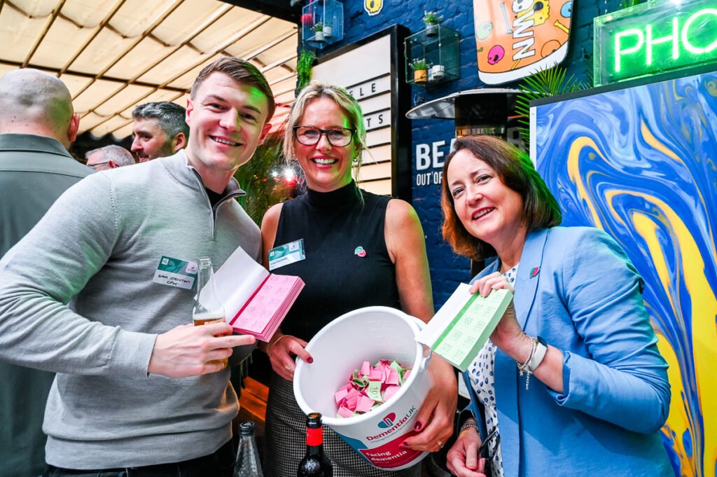 Photo - fund raisers showing off the bucket of raffle tickets at a charity function.