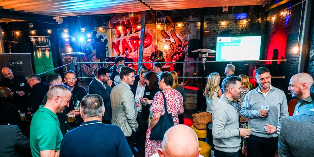 Photo of busy event space with people chatting and band playing