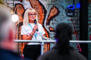Photo of Dementia UK representative with microphone speaking at a charity event