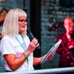 Lady with microphone speaking at a charity event