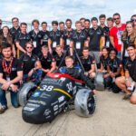 Group photo of student engineers around Meggitt Formula Student race car