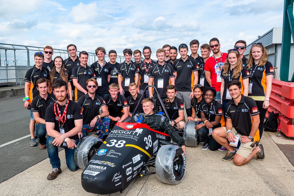Group photo of engineering students around the Meggitt Formula student race car