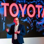Speaker portrait of Nick Duckworth, CEO of Toyota MHUK with large Toyota display behind