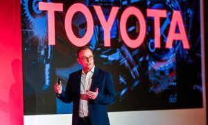 Speaker portrait of Nick Duckworth, CEO of Toyota MHUK with large Toyota display behind