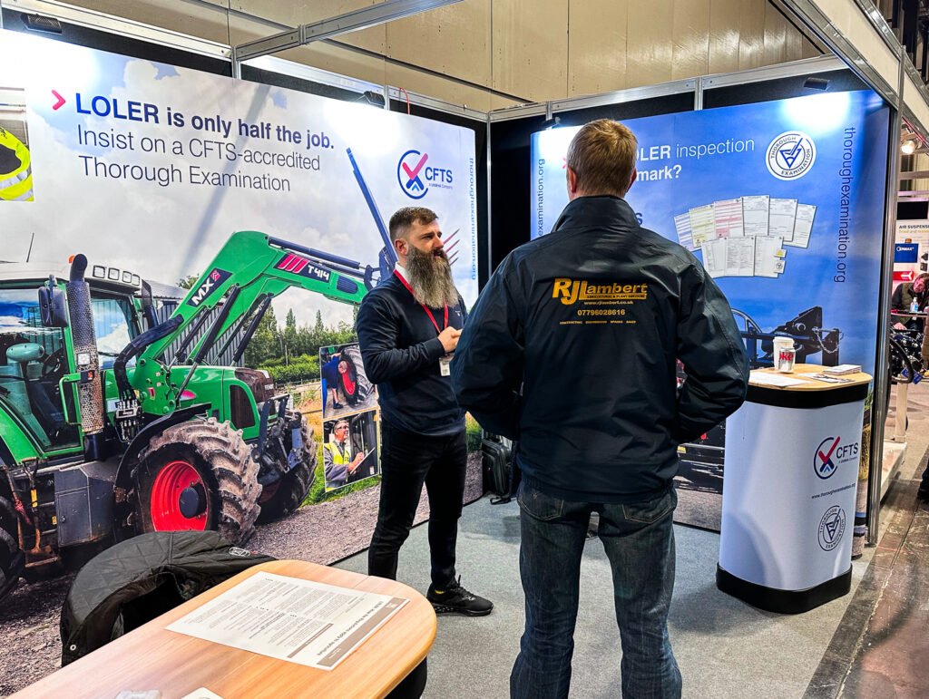 Photo - trade show stand with men talking in front of large display images of agricultural machinery